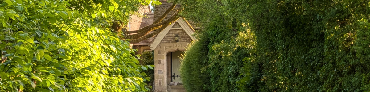 View of Thorpe Village hall peeking through the treest from Hall Lane